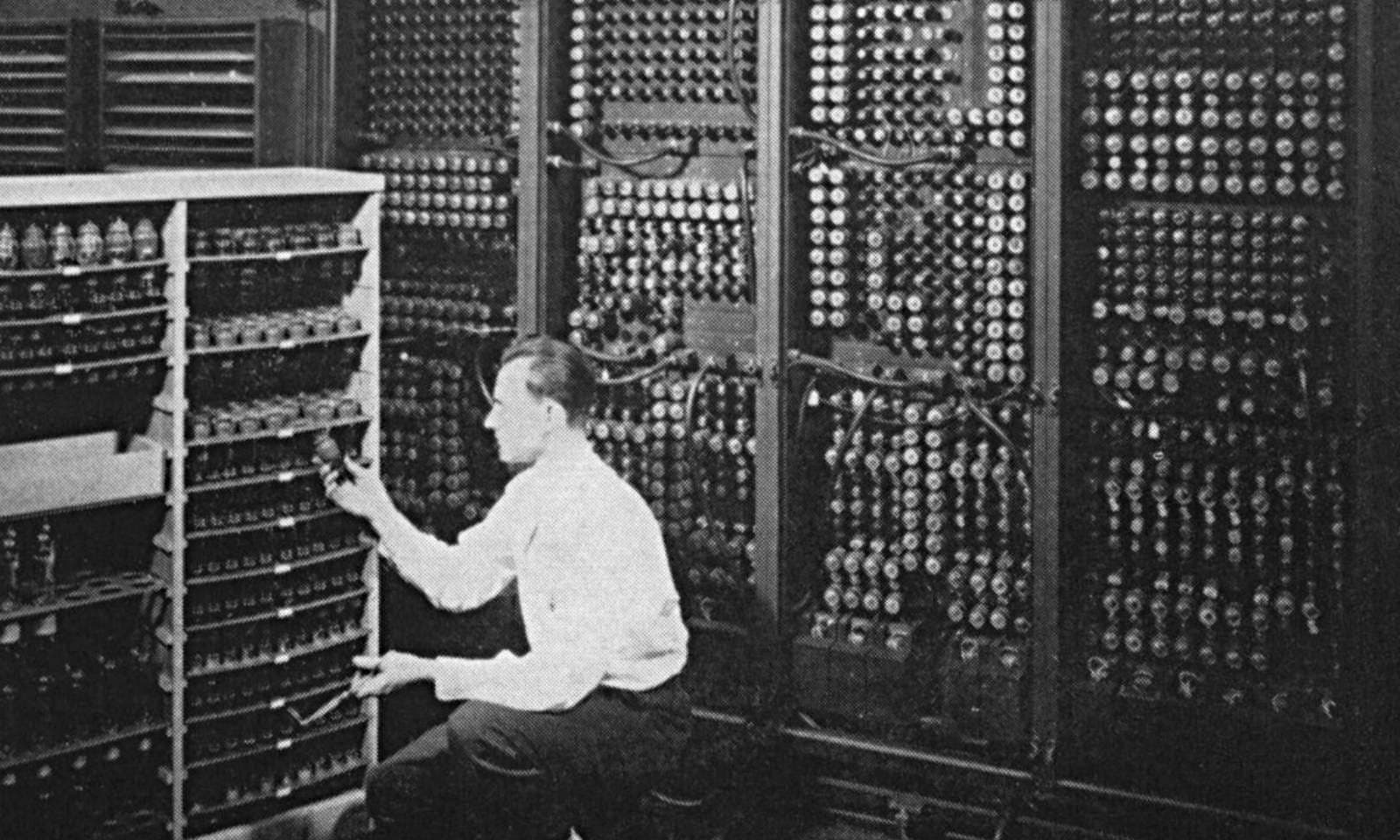Een technicus vervangt een vacuümbuis in een vroege computer zo groot als een kamer, toen programmeren traag en onvergeeflijk was